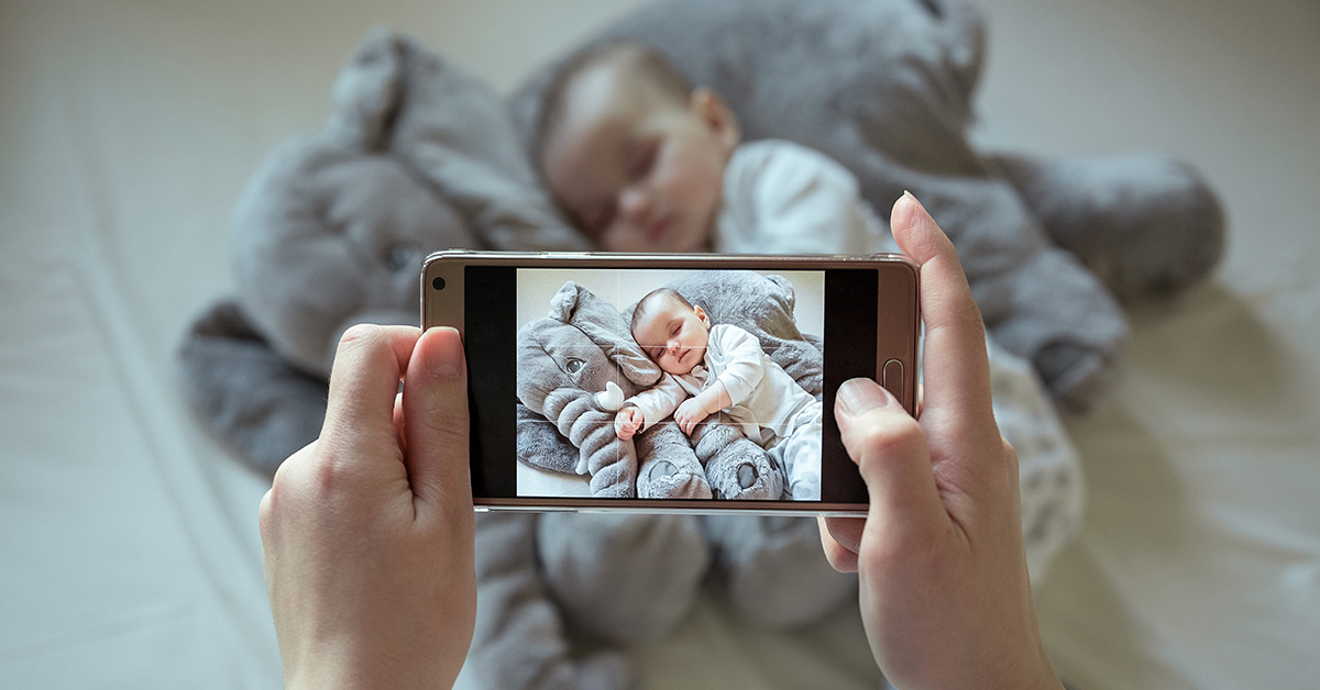 person taking picture of child on smart phone