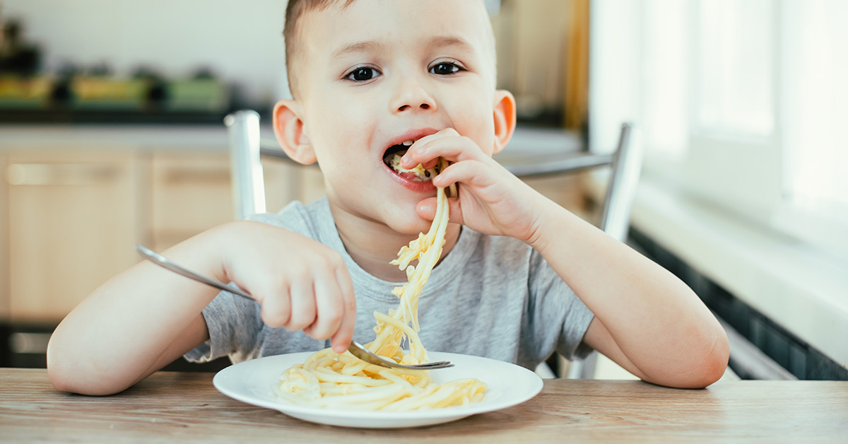 child eating pasta