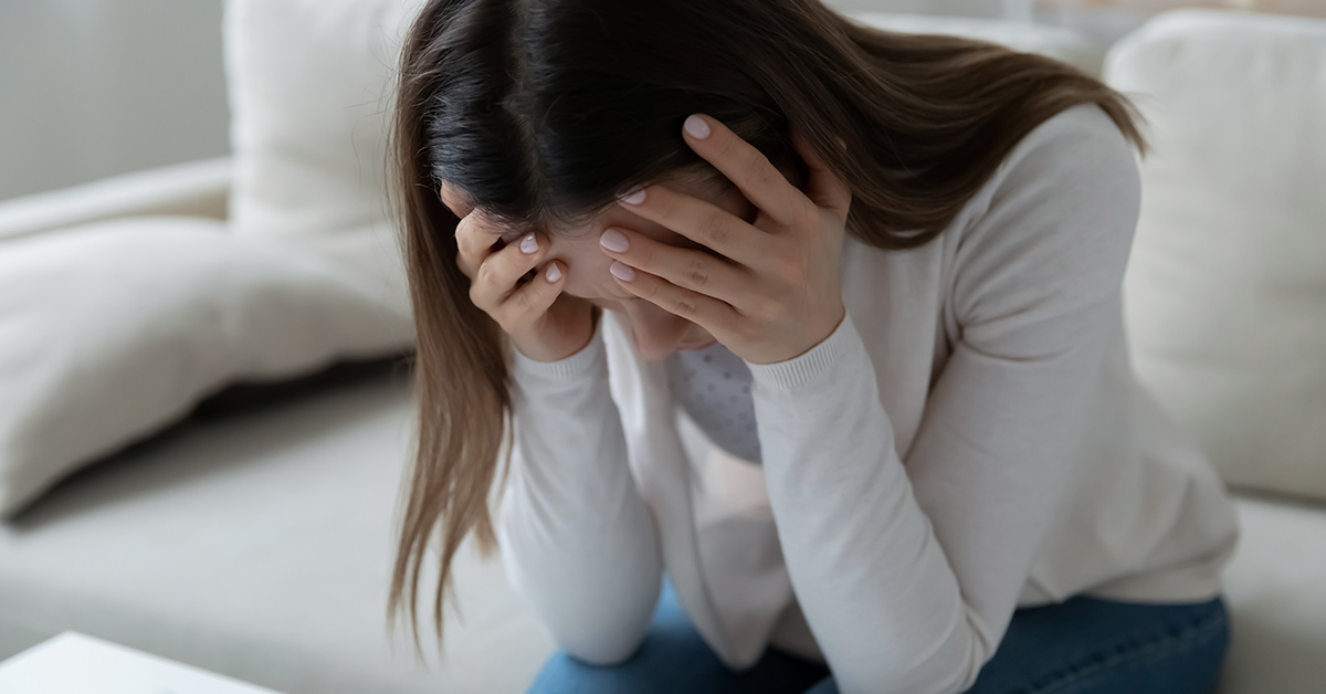 woman holding head in her hands