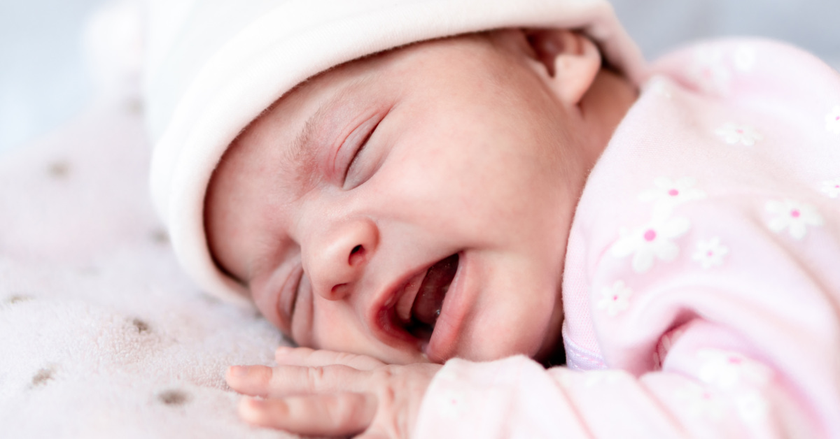 close up of infant laying down wearing a pink hat and clothing