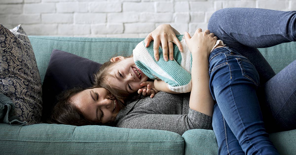 mother snuggling on the couch with young daughter