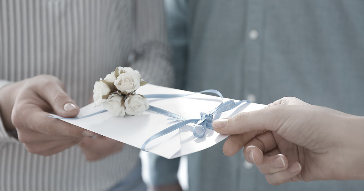 wedding invitation being handed between people