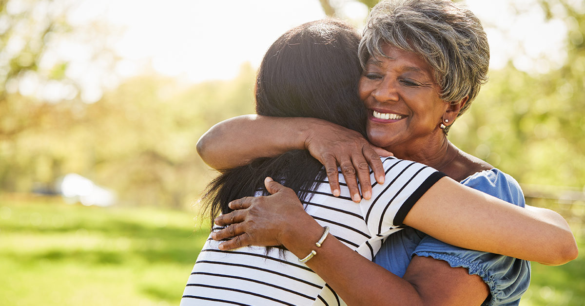 mother and daughter embracing outside on a sunny day