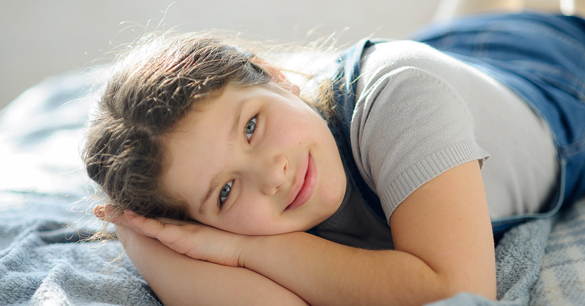 young girl laying on her side with hand underneath the side of her face in a sleeping position