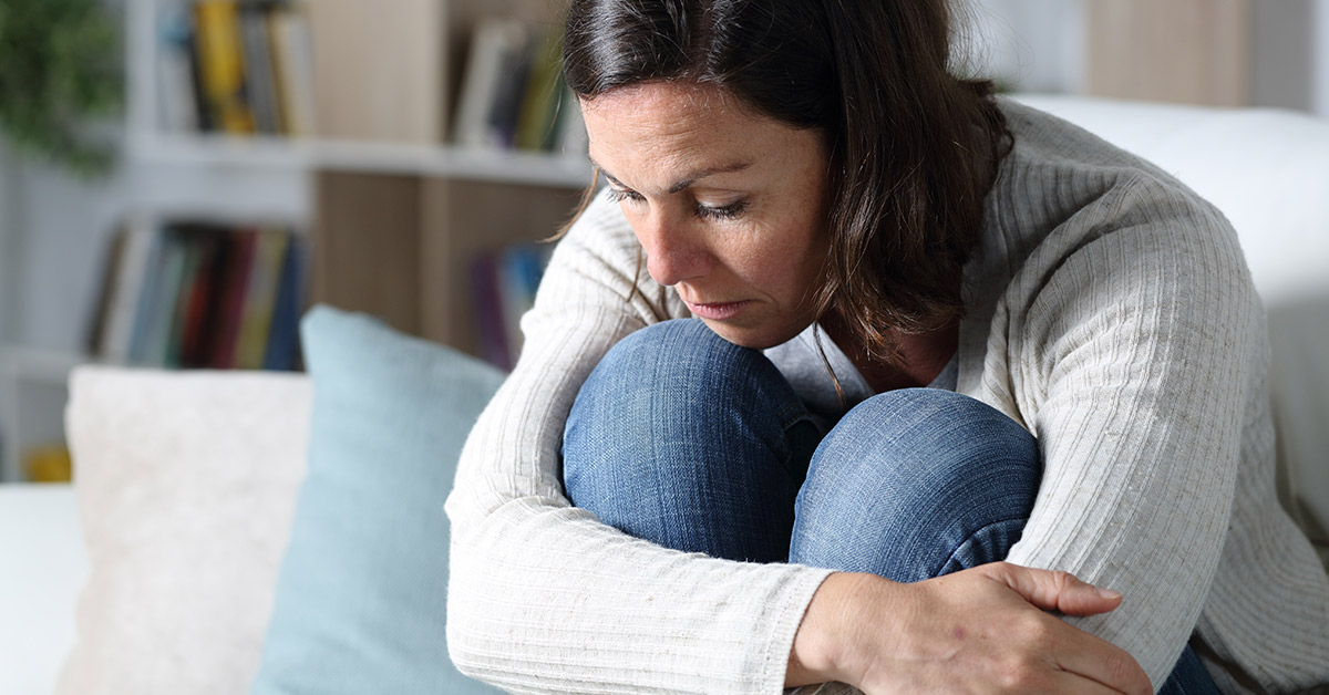 woman sitting on a couch with knees pulled up to her chest