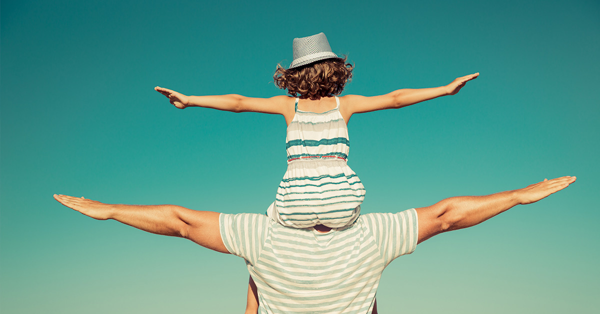 child on parents shoulders, both with arms extended