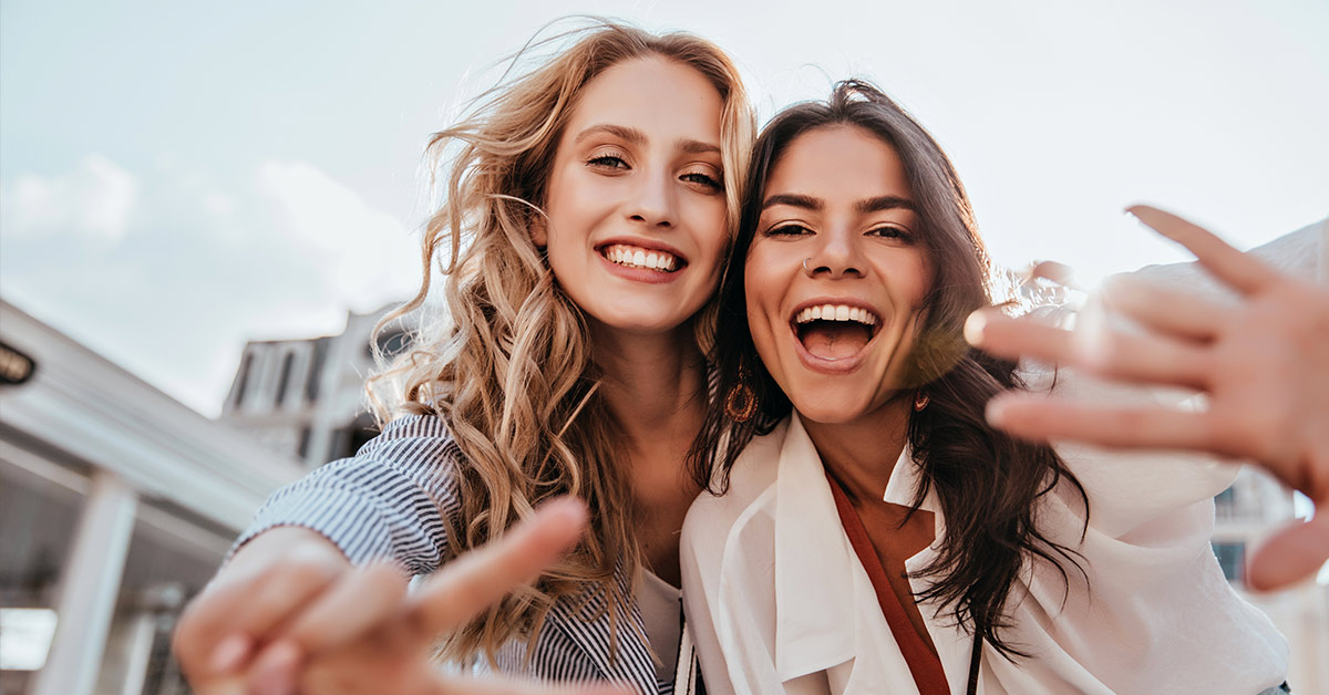 two female friends waving for a photo
