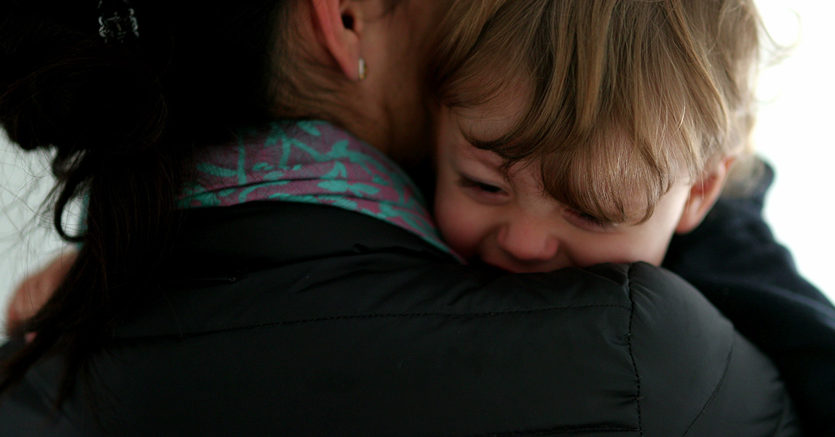 crying son on shoulder of mom