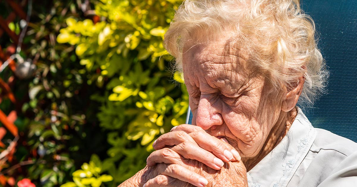 elderly woman with hands clasped together