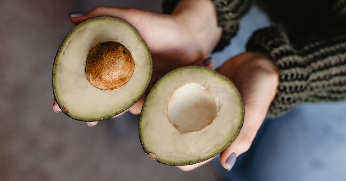 an avocado slices open to reveal its green flesh and pit