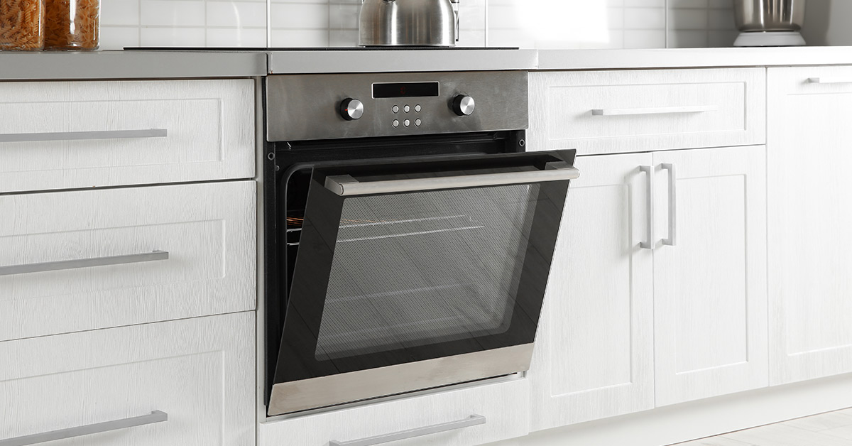 slightly ajar stainless steel oven with white cabinetry in kitchen
