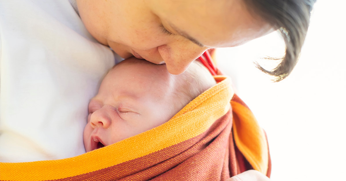 mother kissing the head of her newborn