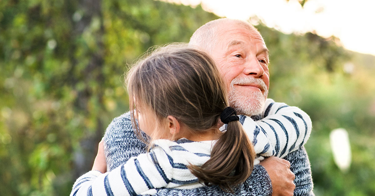 elderly man embracing young girl