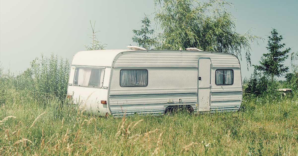 an old camper trailer on a grassy property