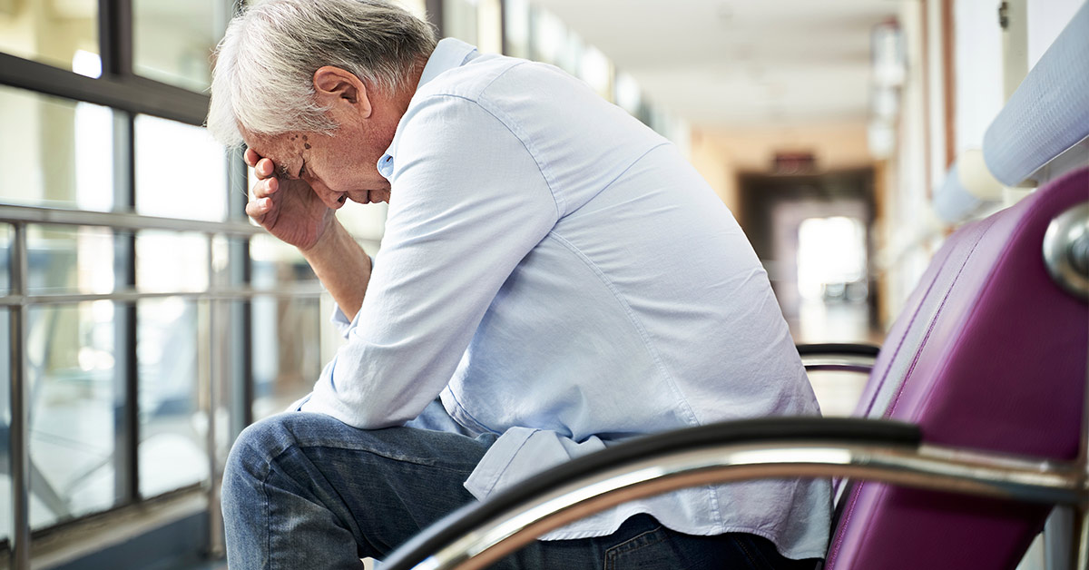 crying middle aged man sitting in a hospital hallway