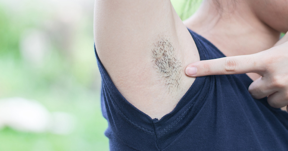 a female pointing towards her armpit hair