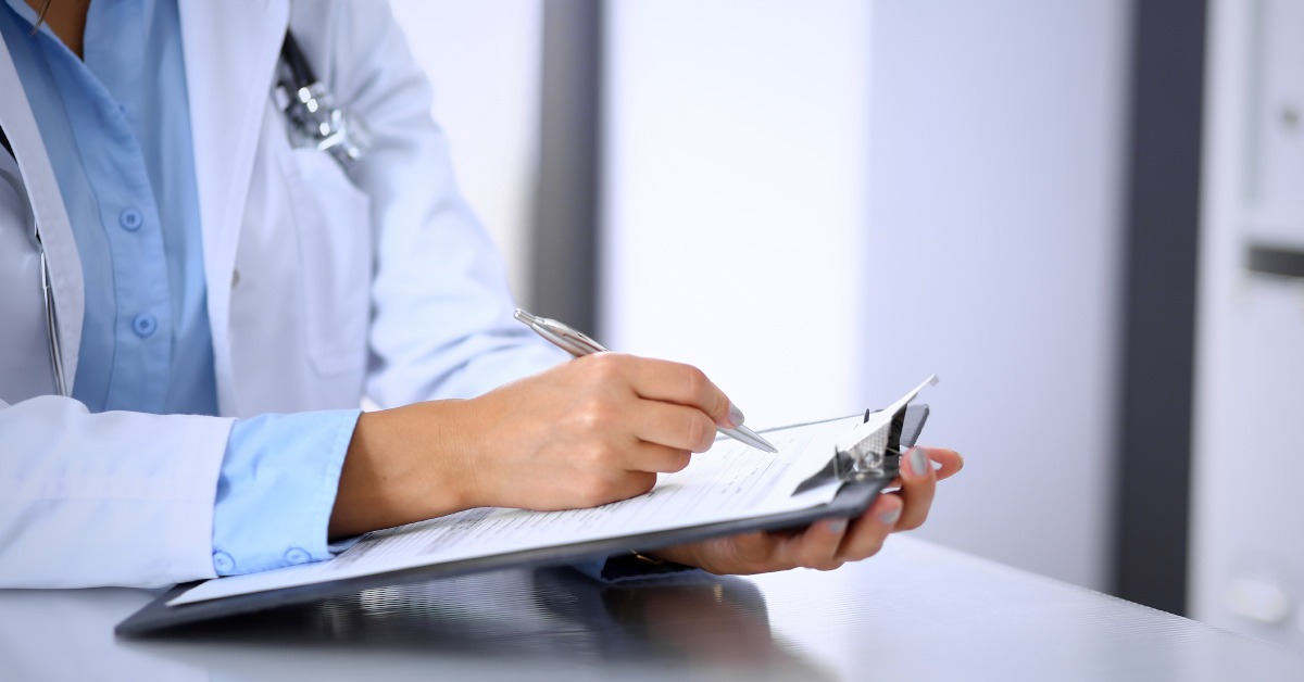 doctor writing on clipboard