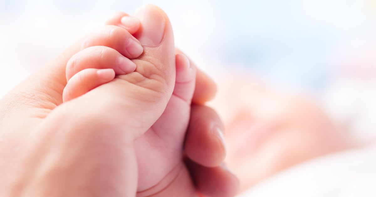 baby's hand holding on to parents thumb