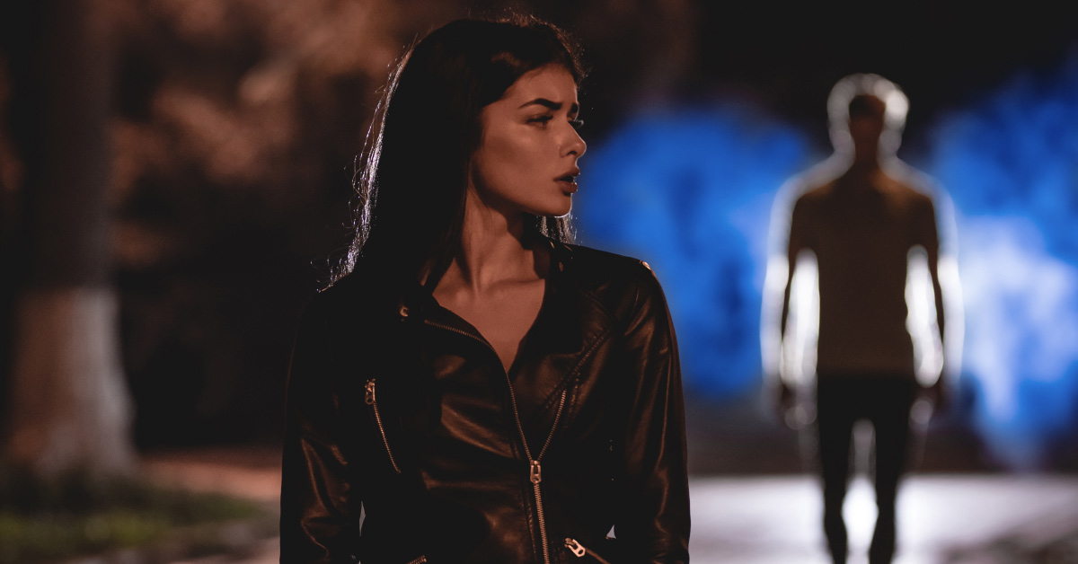 woman walking alone with suspicious stranger walking behind her