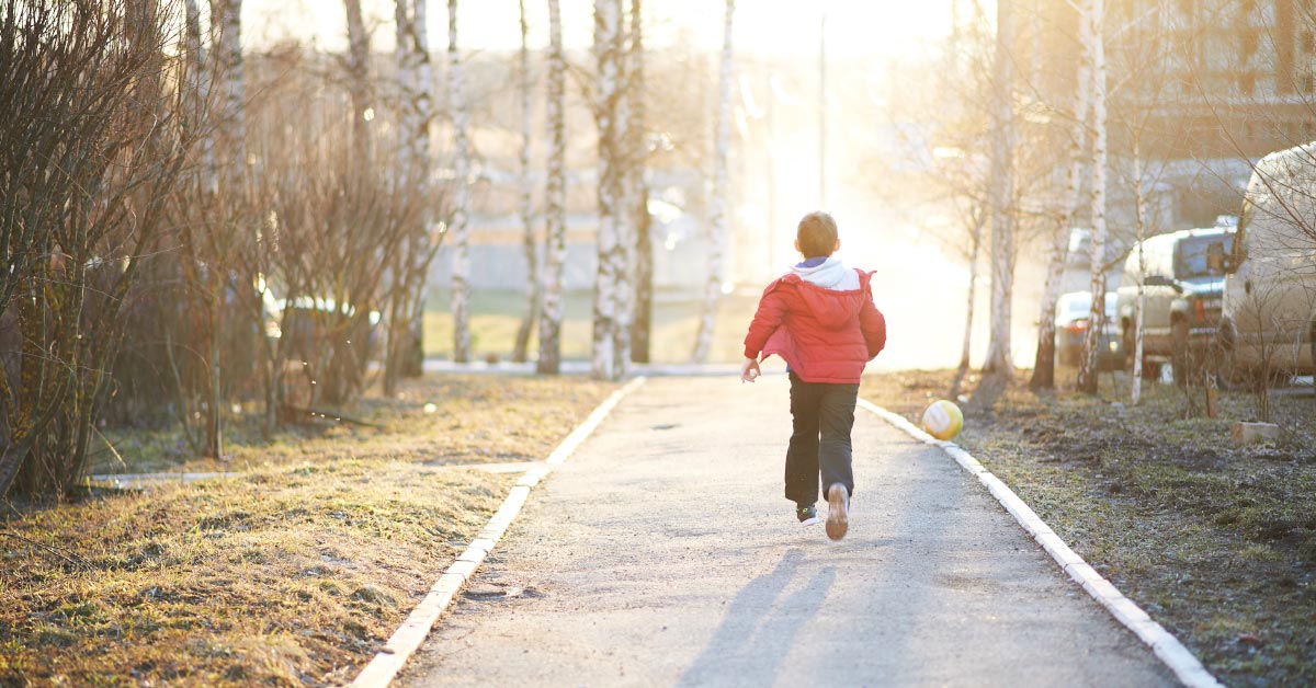 boy walking down a wooded park path at sunset