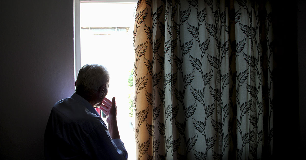 elderly man looking out a window