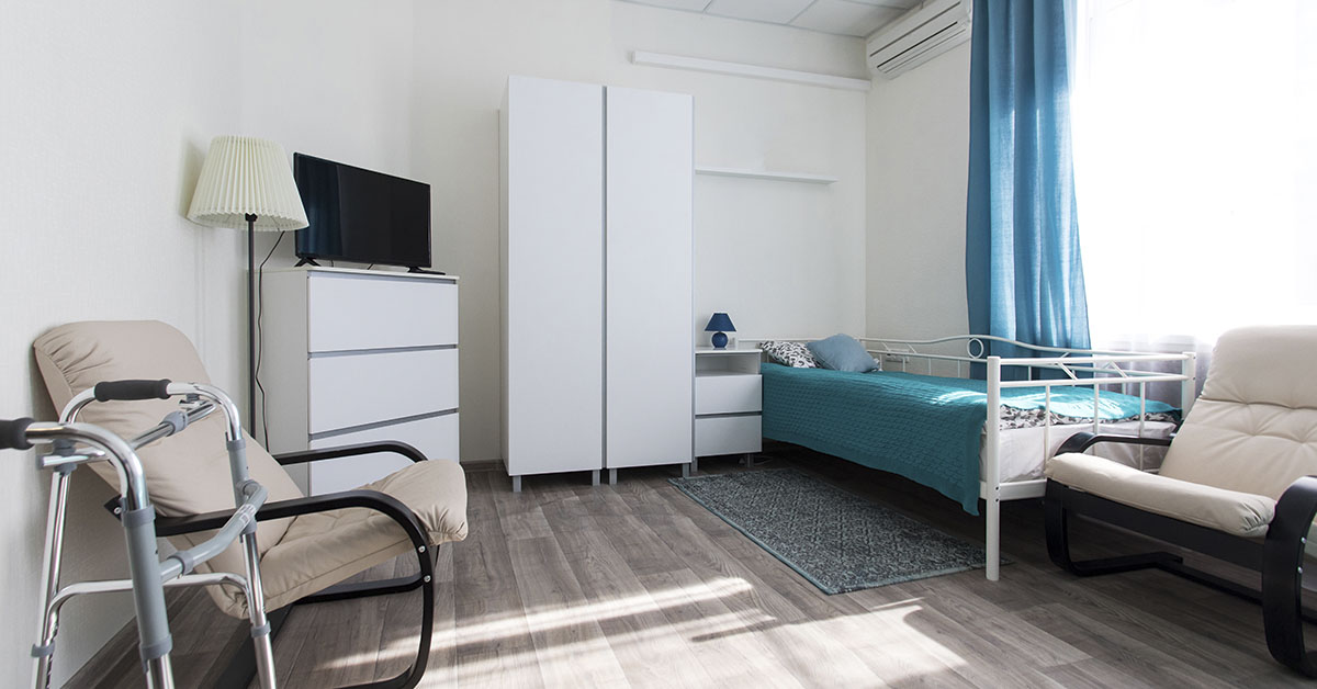 nursing home room with a single bed, dresser, and chair