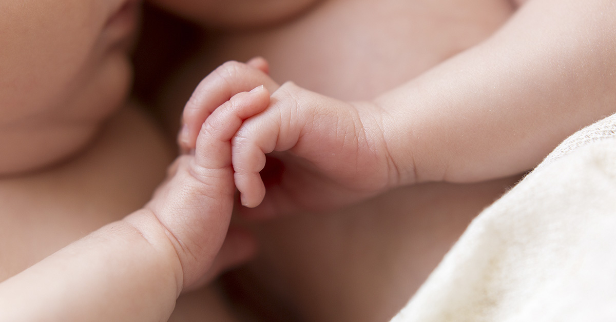twin infants holding each other's hands