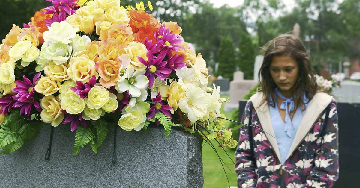 flower on grave stone, person grieving