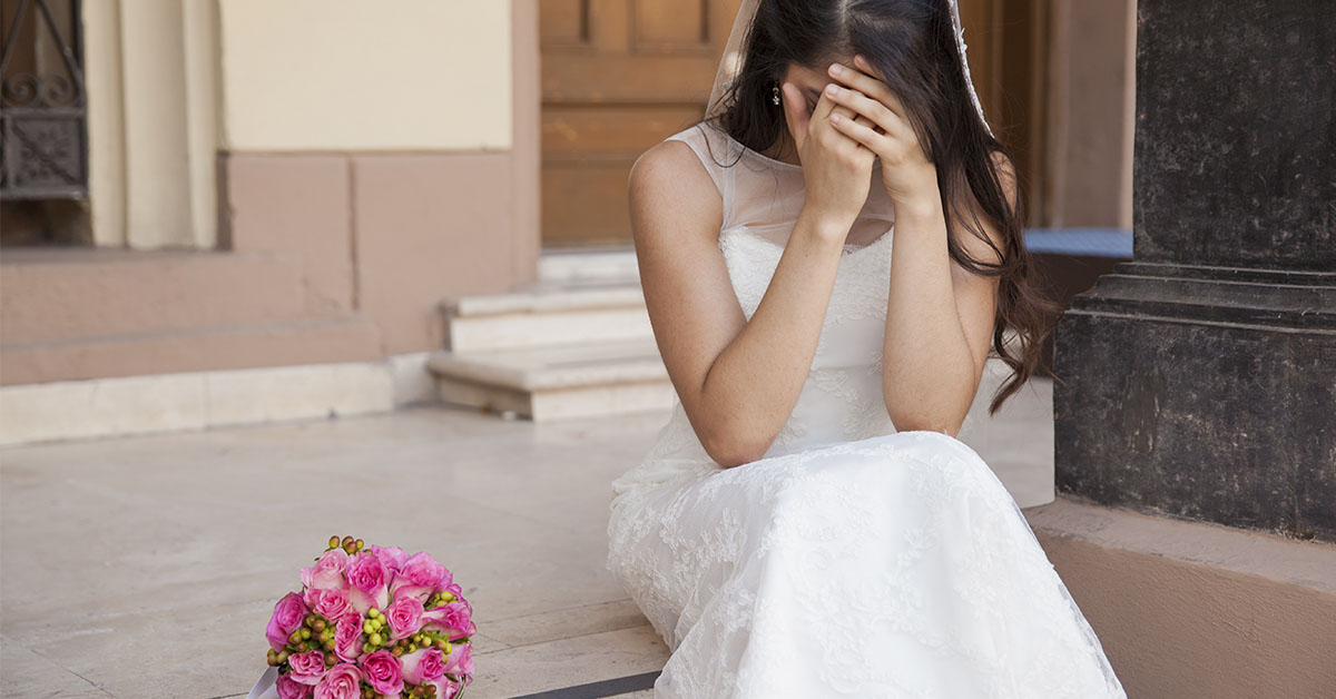 bride in white dress with her head in her hands