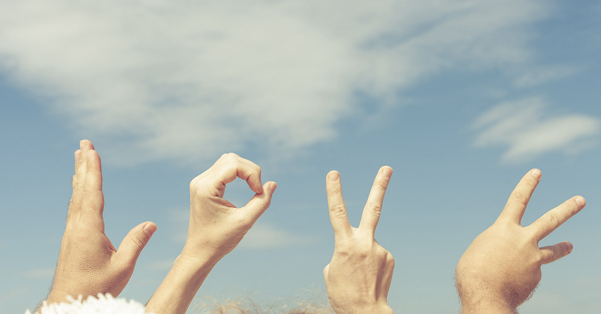 4 hands using sign language with sky background