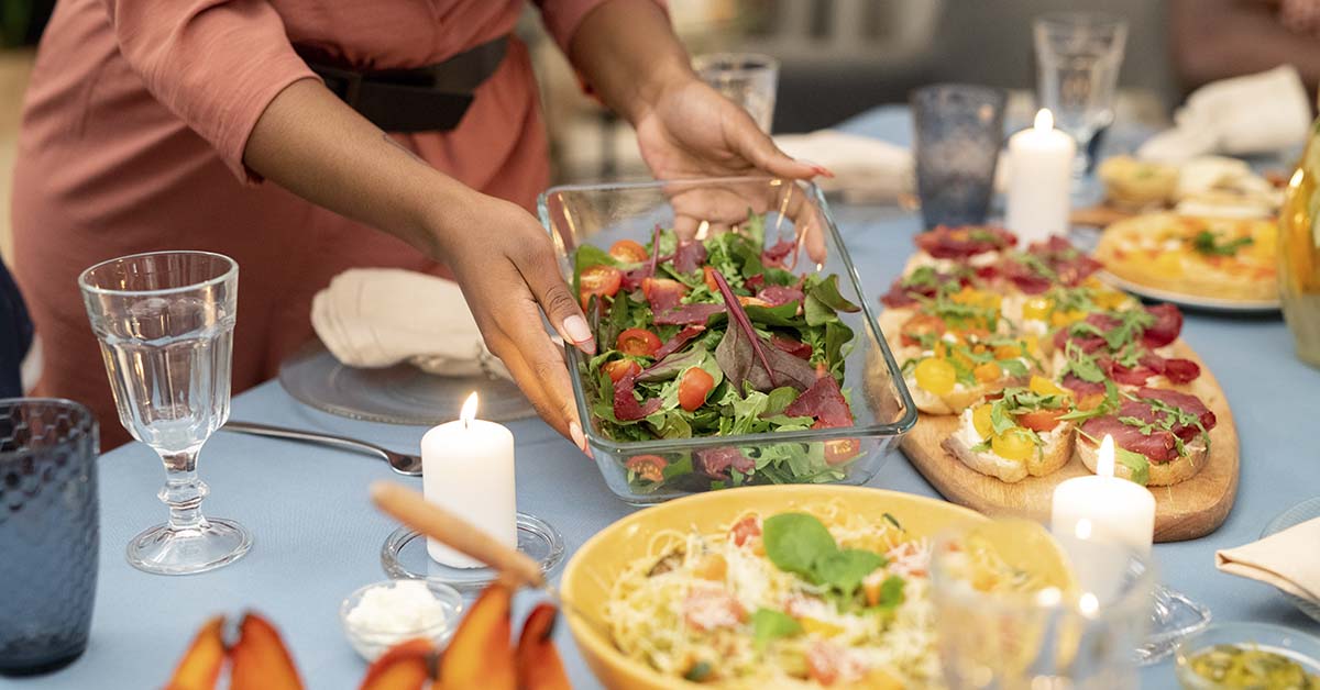 person placing various dishes at a dinner table