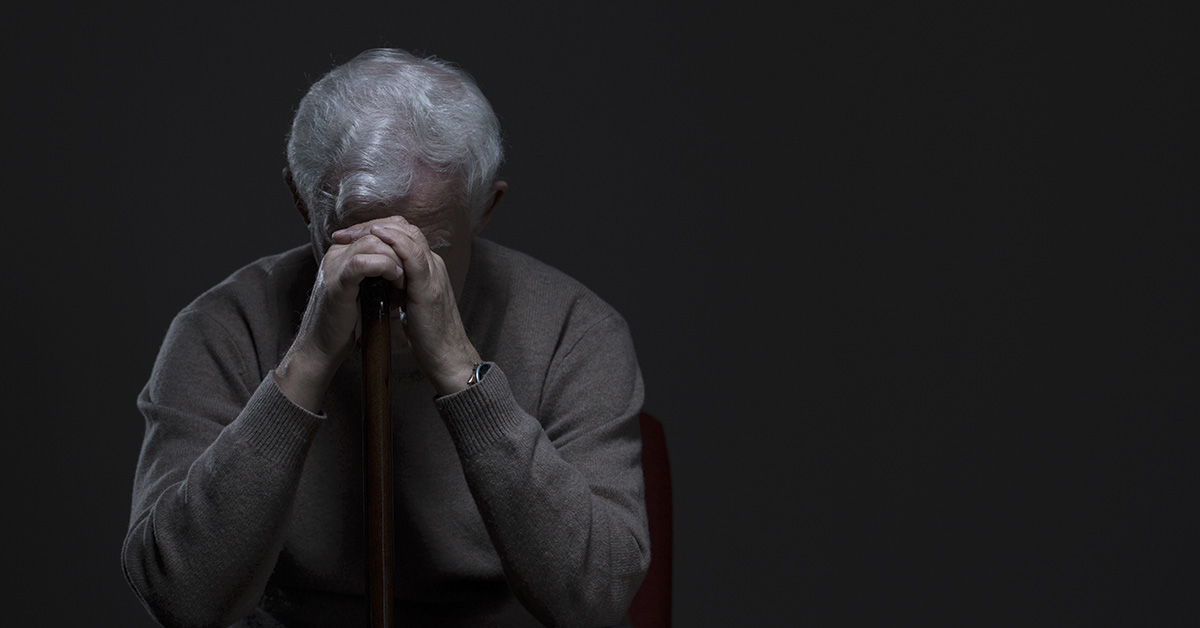 men with hands clasped over face, experiencing grief