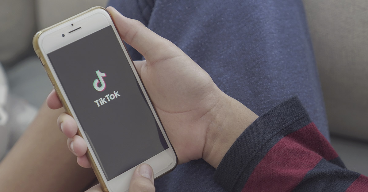 person holding smart phone with tik tok displayed on it
