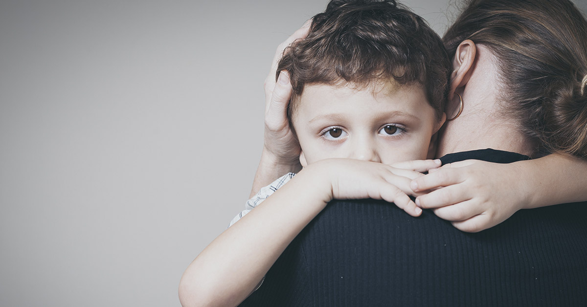 child hugging man with dark gray background