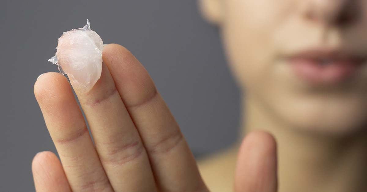 petroleum jelly like substance on woman's middle finger. Healthy and beauty concept