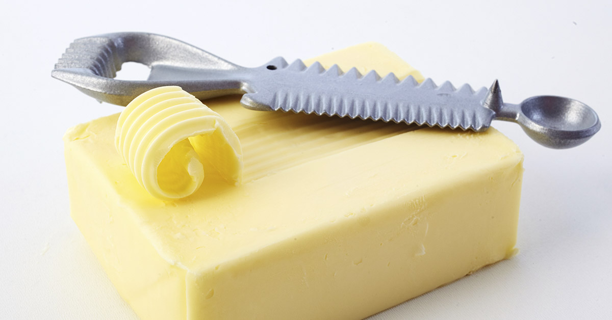 butter curling kitchen tool resting on top of stick of butter