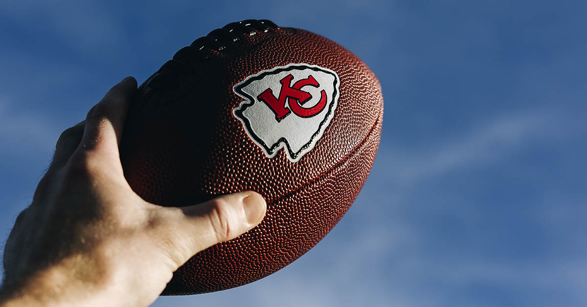 Hand holding football with Kansas City Chiefs logo on it