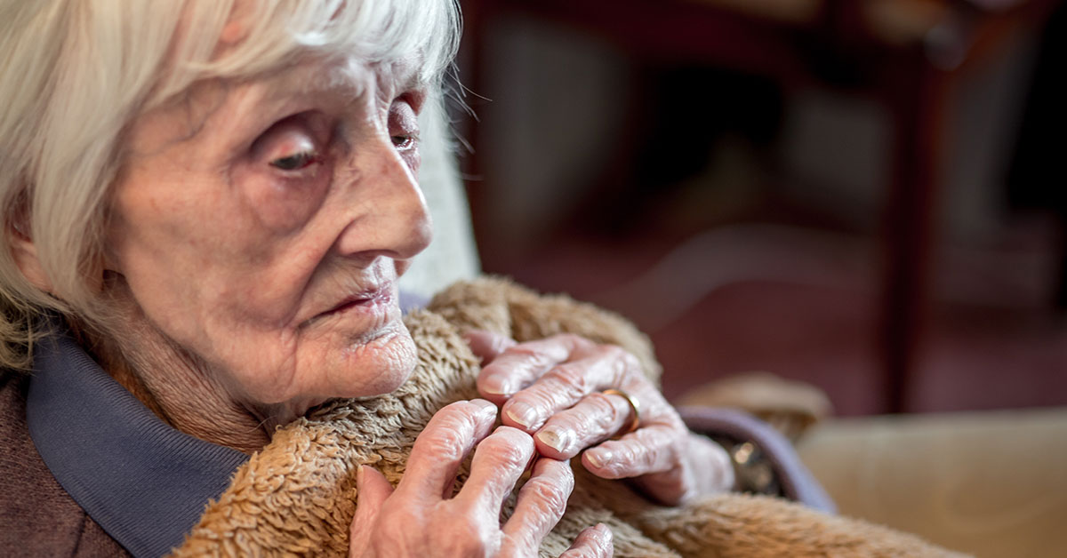elderly woman holding quilt close to body