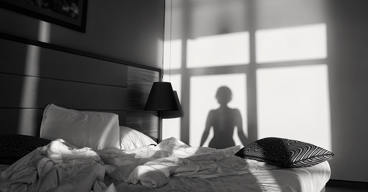Black and White image woman's silouhette can be seen cast on the wall