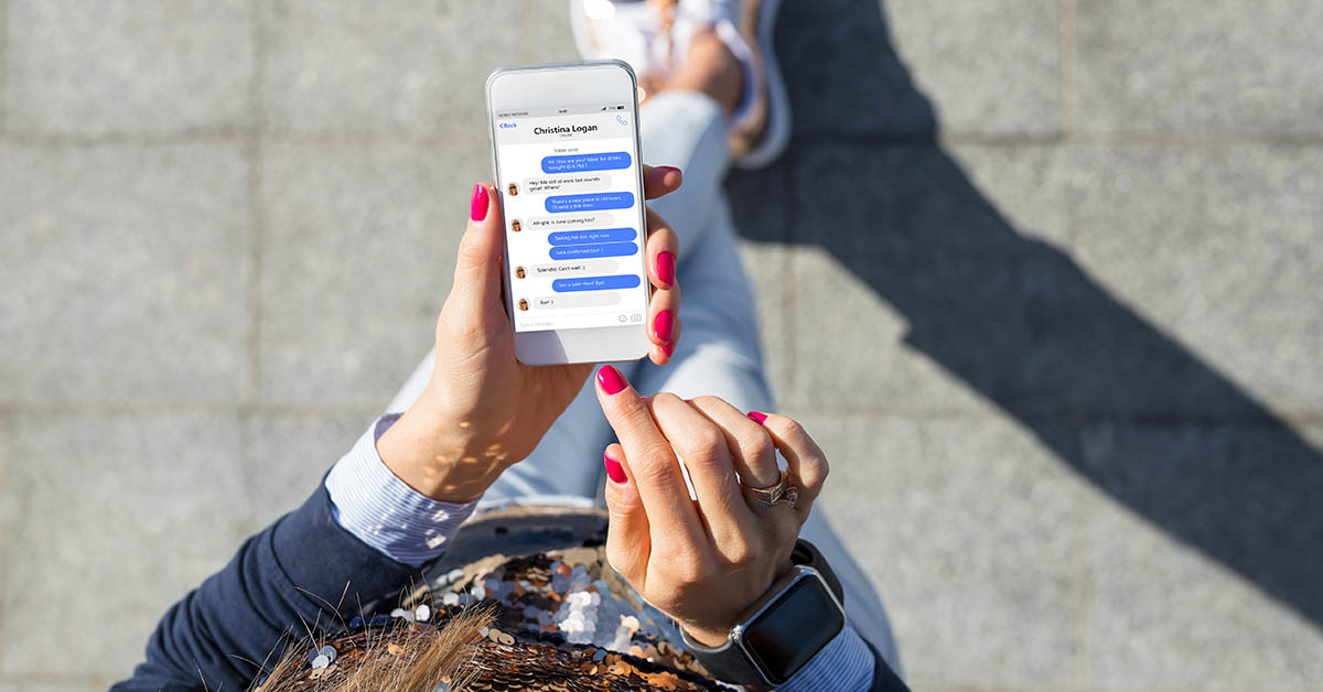 Person holding smartphone using a messaging app while walking