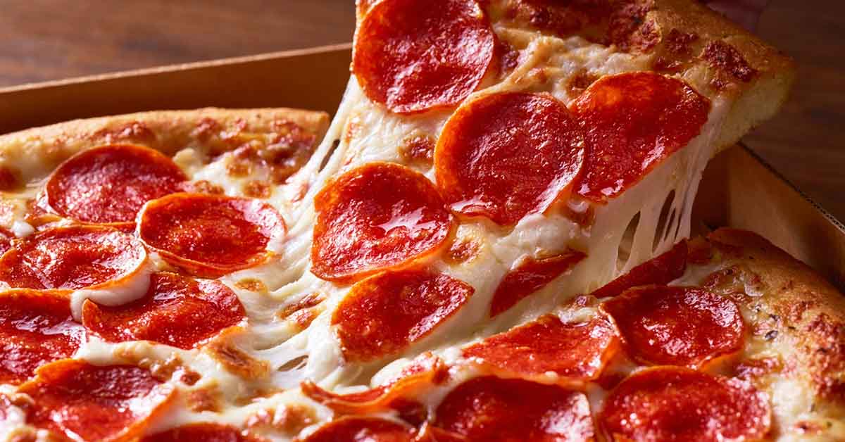 Pepperoni pizza slice being lifted from whole pizza