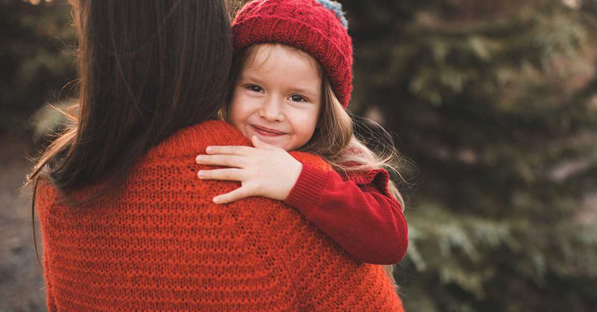 woman holding young girl. Young girl looking over back of woman's shoulder
