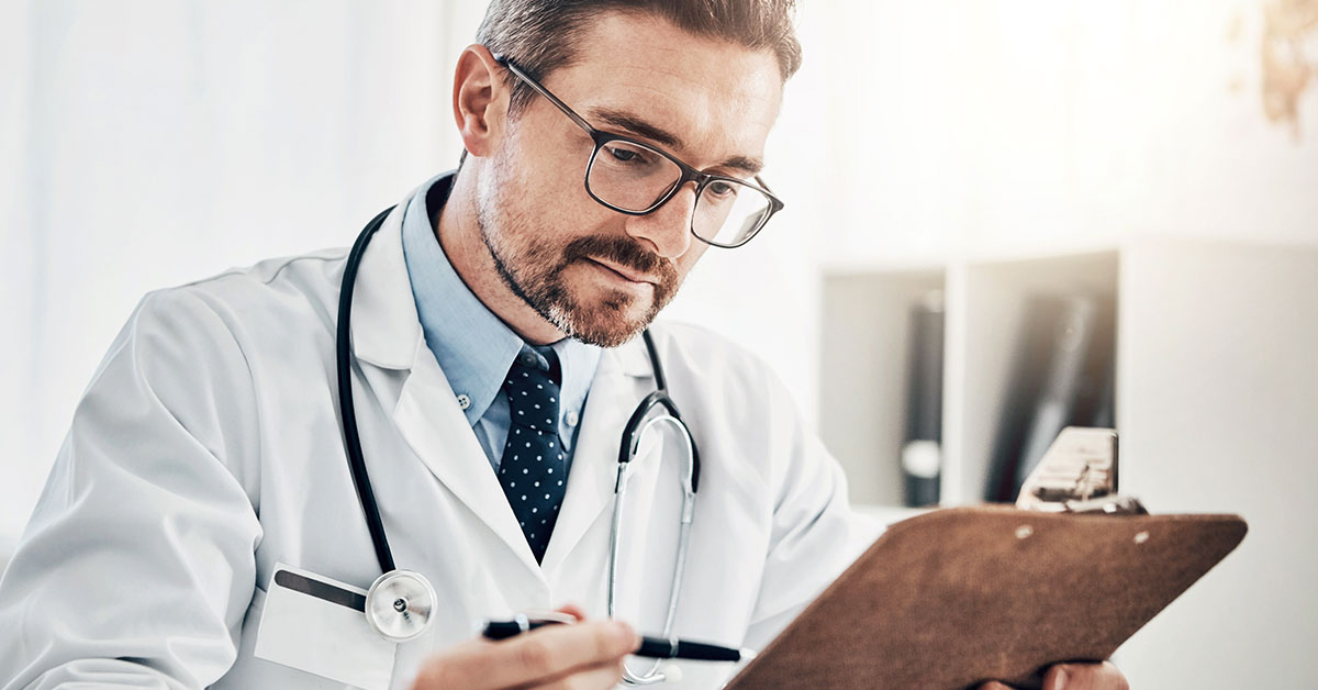 Doctor wearing white coat while holding clip board