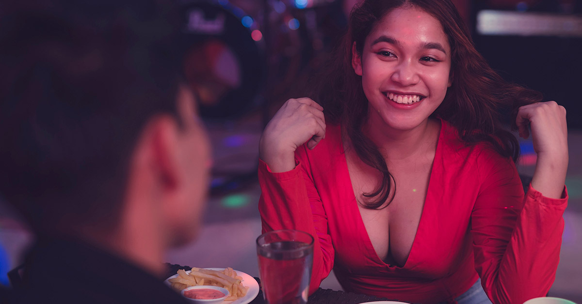 Male and female on date. Woman wearing red dress sitting across from man at table. First date concept