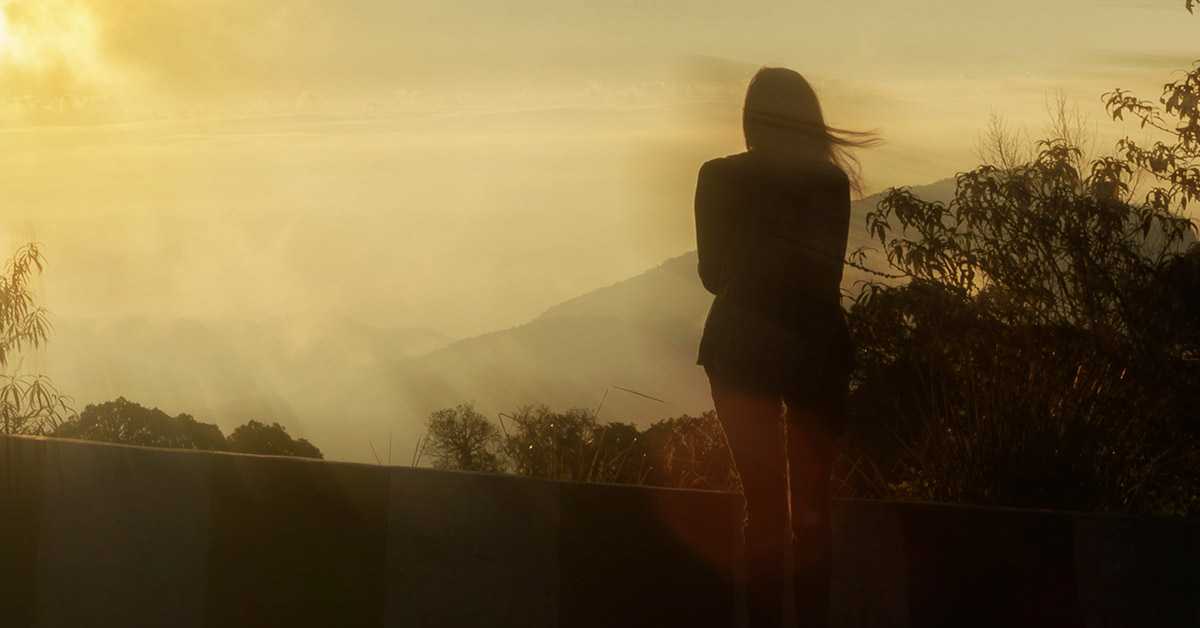woman from mountain top enjoying view of valley below