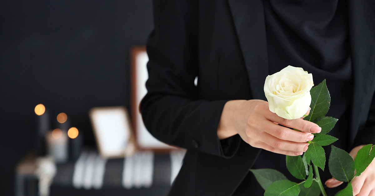 person holding a rose at a funeral