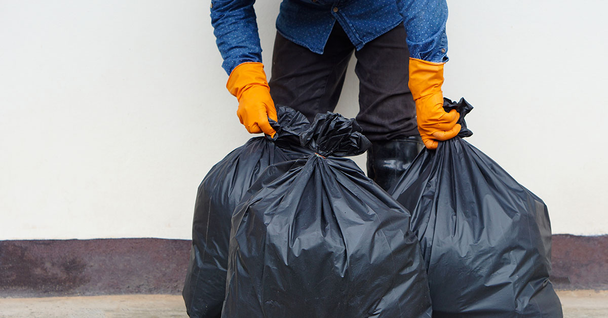 garbage man picking up two garbage bags