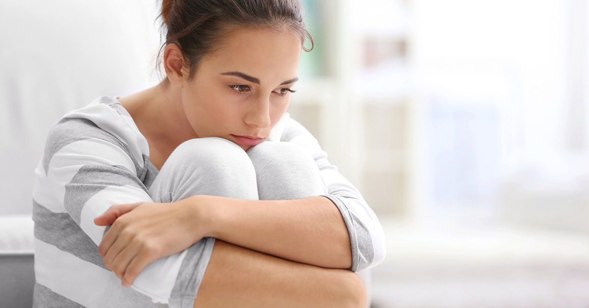 woman sitting with arms around legs and knees under chin. Depression/sadness/rumination