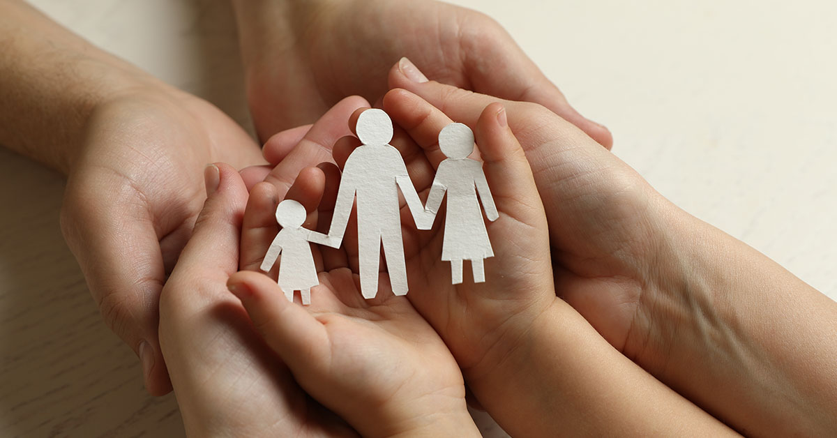 paper cut out of a mother and father and child being held the the ends of a child, mother and father. Family cohesion concept