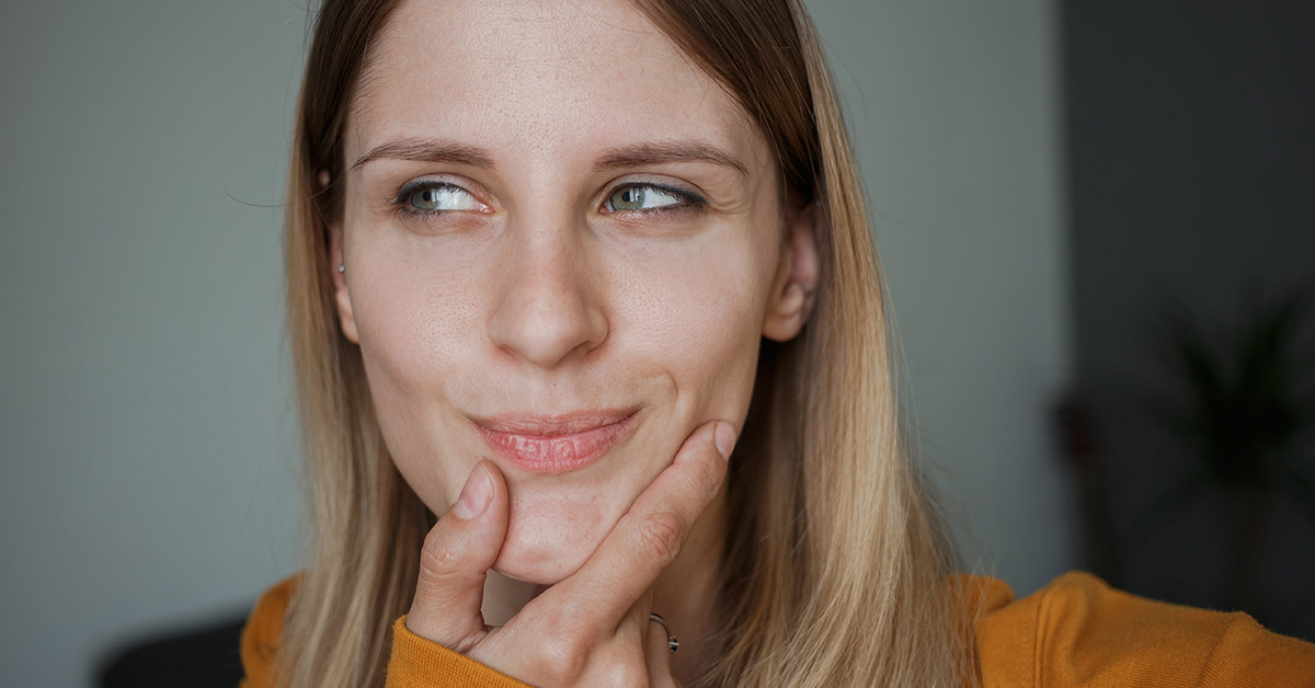 Grinning woman with hand placed under chin.